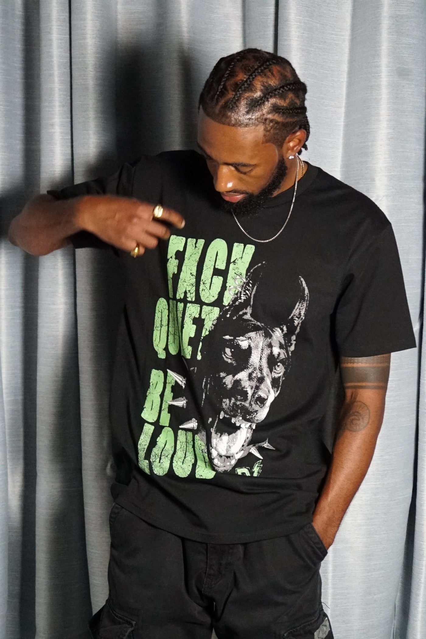 Person wearing a black t-shirt with graphic design and text on a corrugated metal background