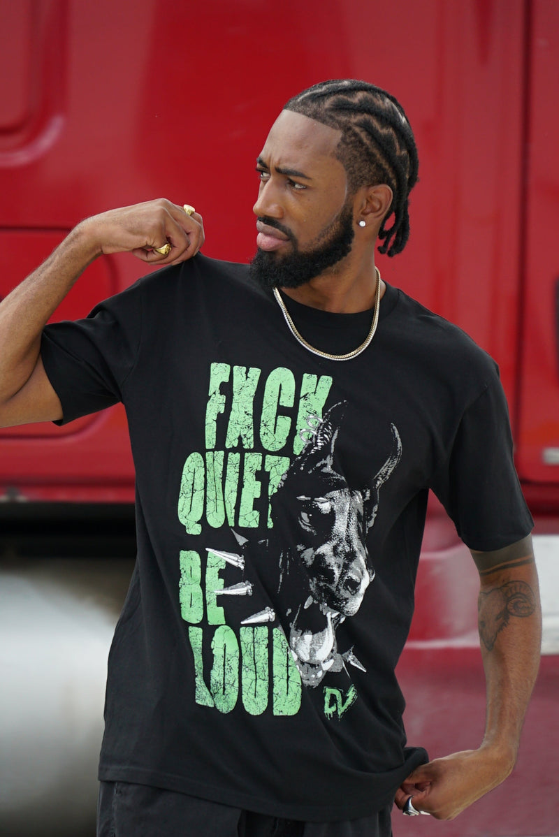 Person wearing a black t-shirt with green text and graphic design, standing in front of a red vehicle.